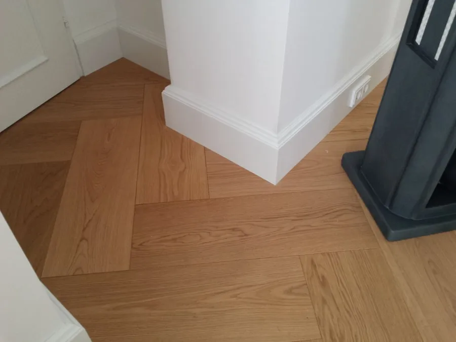 Heller Dielenboden am Übergang zu einem dunklen Kaminofen