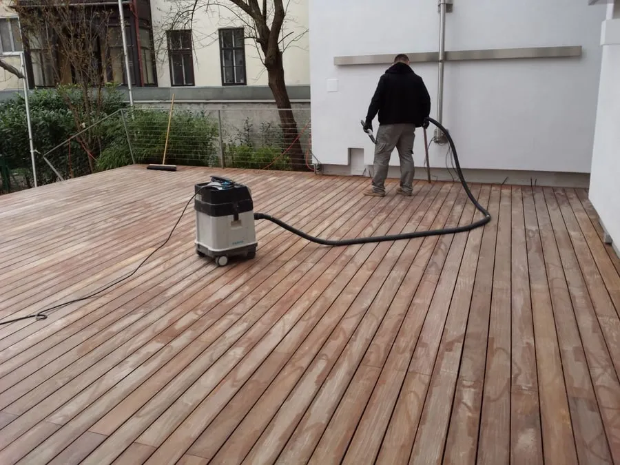 Handwerker arbeitet mit einem Sauger auf einer Holzterrasse
