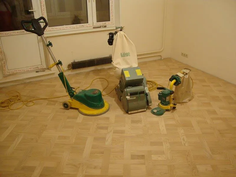 Schleifmaschinen in einem leeren Zimmer mit Fischgrätparkett